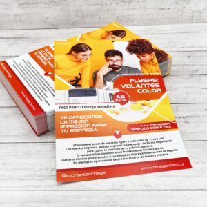 Volantes publicitarios a color impresos por Imprenta Omega, apilados sobre una superficie de madera clara.