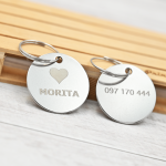 Tags circulares de acero inoxidable grabados con láser, con nombre y número personalizados, sobre mini pallet de madera con logo Omega Printmaster.