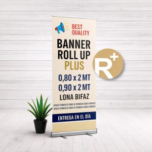 Banner Roll Up Plus de Imprenta Omega con estructura de aluminio y lona bifaz impresa, acompañado de planta decorativa sobre fondo de madera clara.