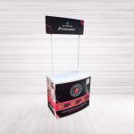 Vista frontal de mostrador promocional personalizado con cenefa publicitaria y gráfica en vinilo.
