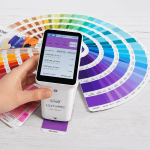 Colorímetro LS173 realizando lectura de color sobre una guía Pantone profesional.