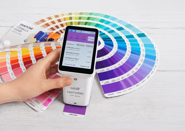 Colorímetro LS173 realizando lectura de color sobre una guía Pantone profesional.