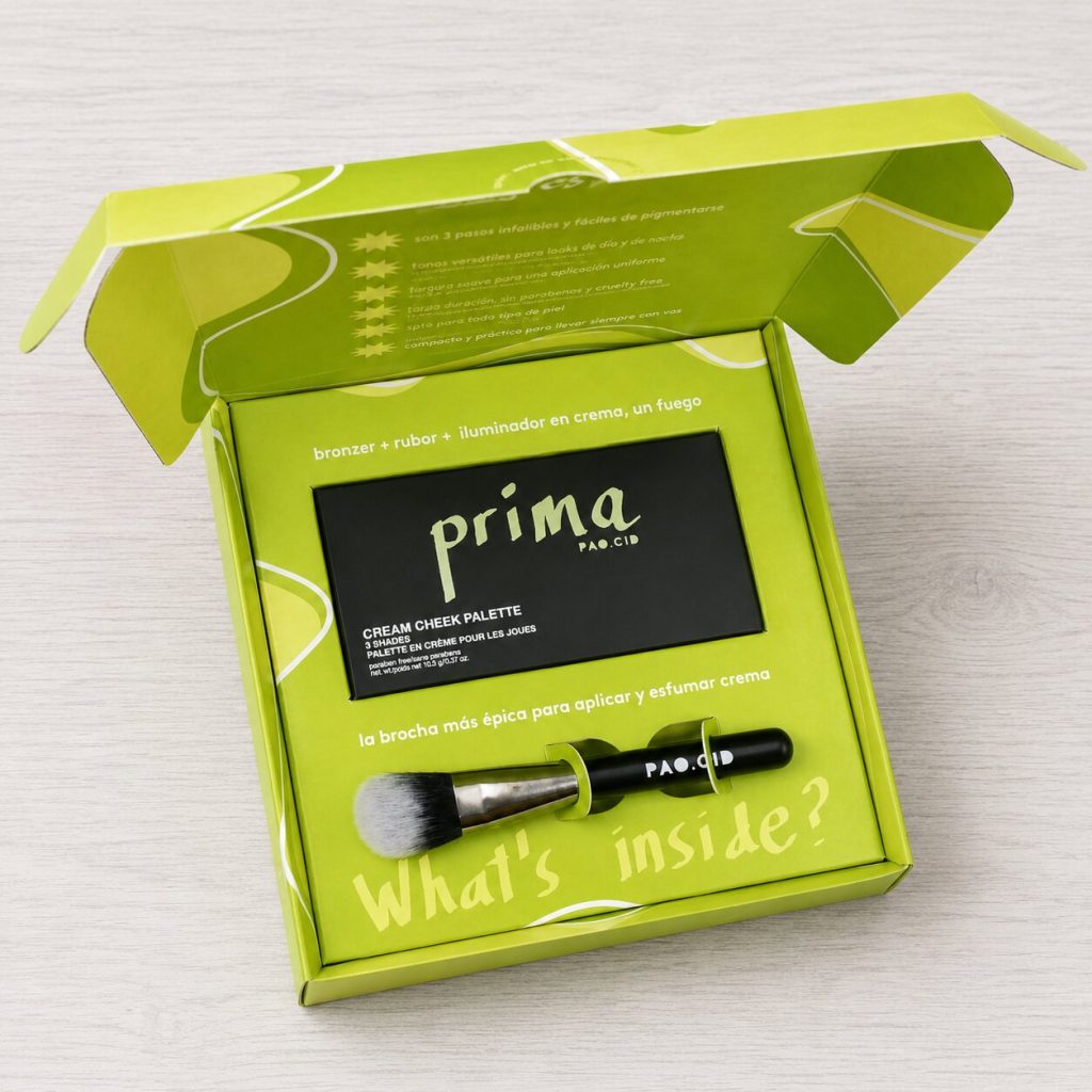 Packaging personalizado Prima PAO.CID en caja autoarmable verde con interior impreso, paleta de maquillaje y brocha integrada.